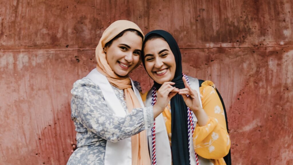 Twin sisters Iman, left, and Salam make wolf hands at the Wolf Ears before graduation.