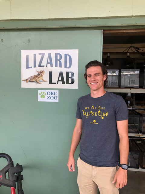 Sam in front of a sign that says Lizard Lab with picture of a lizard